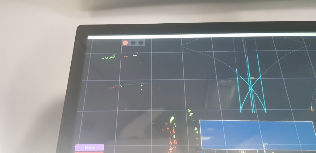 운전석 뒤편의 스크린에는 파란색 부분의 횡단보도와 함께 주변을 지나가는 연두색 점 모양의 사람들이 보인다. /사진=최우영 기자