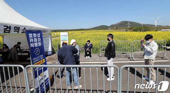 제38회 제주유채꽃축제가 개막한 6일 제주 서귀포시 표선면 가시리 유채꽃광장에서 방문객들이 입장 전 발열체크를 하고 있다. 서귀포시는 유채꽃광장에 입장할 수 있는 순간 최대 수용인원을 350명으로 제한해 축제를 운영하고 있다.2021.4.6/뉴스1 © News1 오현지 기자