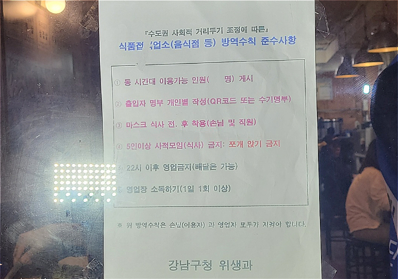 12일 강남구청과 강남구보건소 위생과 직원들이 강남구 신사동 가로수길의 음식점들을 돌아다니며 부착한 방역지침 준수 안내문/사진=임소연 기자