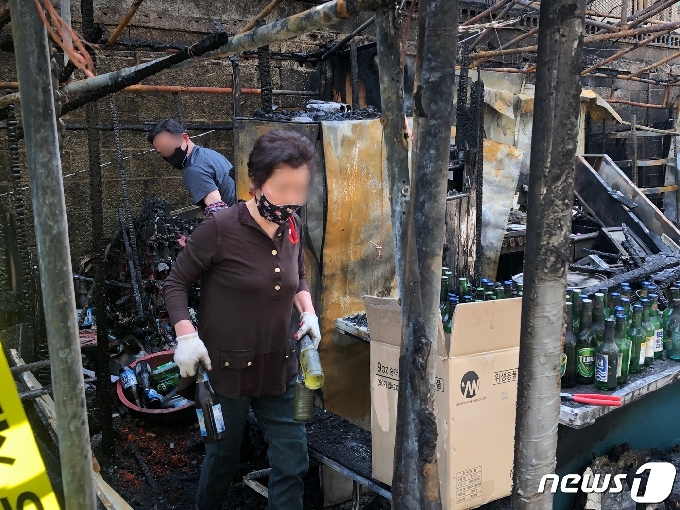 21일 오전 부산 동구 부산역 풍물시장 포장마차 골목에서 화재 피해를 입은 상인이 주류 등 불에 그을린 집기류를 정리하고 있다.2021.4.21 /뉴스1 백창훈 기자©
