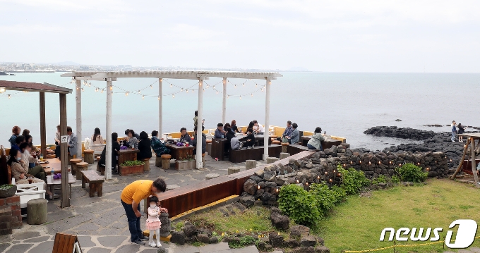 낮 최고기온이 25도까지 오르며 초여름 날씨를 보인 22일 오후 제주시 애월읍 한담해변에서 관광객들이 여유를 만끽하고 있다. 관광객을 중심으로 확산세가 이어지고 있는 제주에서는 이달에만 총 60명의 확진자가 발생했으며, 이중 66%에 달하는 40명이 관광객이거나 다른 지역 확진자와 접촉한 도민, 해외 입국자로 파악됐다.2021.4.22/뉴스1 © News1 오현지 기자