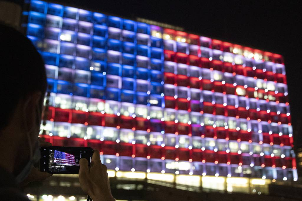 [텔아비브=AP/뉴시스]7일(현지시간) 이스라엘 수도 텔아비브에서 한 남성이 미국 국기 조명으로 한 면이 장식된 텔아비브 시청사를 찍고 있다. 현지 관계자는 미국과의 연대와 민주주의에 대한 지지 표시로 미국 국기를 시청사에 투영했다고 밝혔다. 2021.01.08.