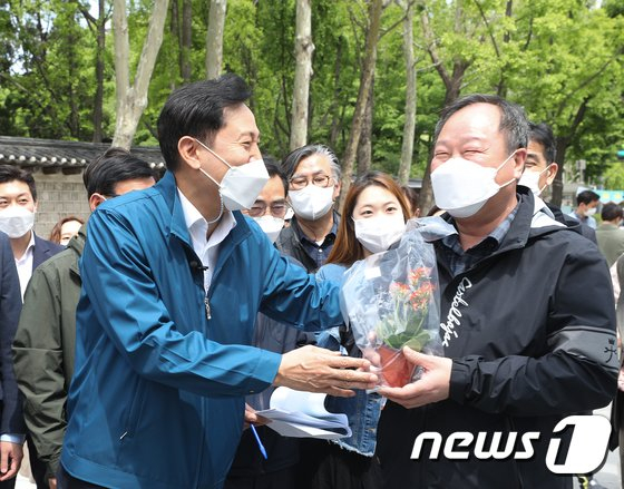 오세훈 서울시장(왼쪽)이 지난 6일 오전 서울 종로구 세종대로 사람숲길에서 구매한 꽃을 김인호 서울시의회 의장에게 선물하고 있다./사진=뉴스1