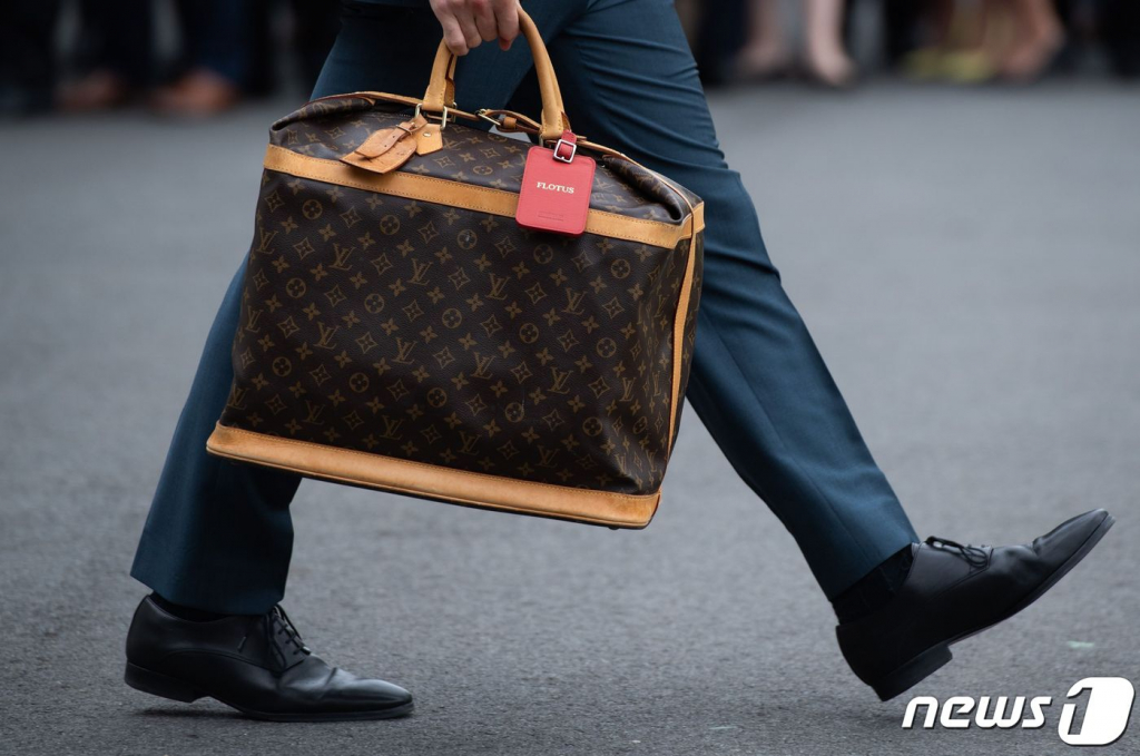 (워싱턴 AFP=뉴스1) 우동명 기자 =  27일(현지시간) 워싱턴 백악관에서 도널드 트럼프 미국 대통령 부인 멜라니아 여사의 보좌관이 전용헬기를 타는 멜라니아 여사의 루이뷔통 가방을 들고 있다.   ? AFP=뉴스1  