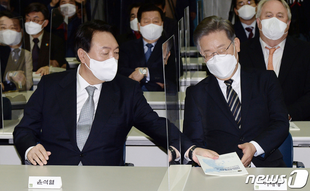 (서울=뉴스1) 국회사진취재단 = 9일 오후 서울 마포구 연세대학교 신촌캠퍼스 김대중도서관에서 열린 김대중 대통령 노벨평화상 수상 21주년 기념식에서 윤석열 국민의힘 대선후보가 이재명 더불어민주당 대선후보에게 기념식과 관련한 안내책자를 전해주고 있다. 2021.12.9/뉴스1