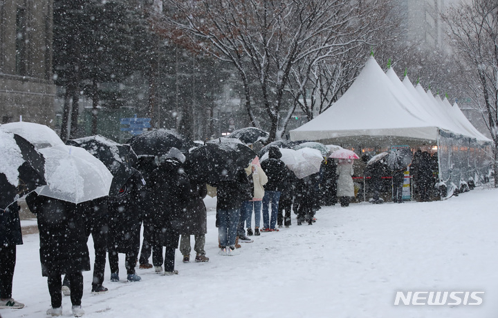 올 겨울 첫 대설주의보가 발령된 지난 18일 오후 서울시청 코로나19 임시선별검사소에서 시민들이 검사를 받기 위해 눈을 맞으며 줄서 기다리고 있다. / 사진 = 뉴시스