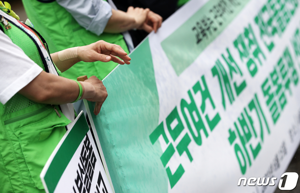 (서울=뉴스1) 오대일 기자 = 15일 오전 서울 종로구 서울시교육청 앞에서 열린 전국교육공무직본부 서울지부의 전국돌봄전담사 하반기 투쟁선포 기자회견에서 한 참가자가 양 손목에 파스를 붙힌 채 피켓을 들고 있다. 사진은 기사 내용과 무관. 2021.6.15/뉴스1