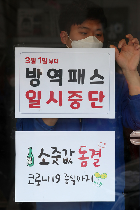 (대구=뉴스1) 공정식 기자 = 28일 오후 대구 중구의 한 음식점 유리문에 식당 직원이 3월 1일부터 시행되는 방역패스 일시중단 관련 안내문을 붙이고 있다.  방역패스 일시중단 안내문 아래 소줏값 동결 안내문이 붙어 있다. 음식점 주인은 "소주 출고가는 인상됐지만 코로나19 확산 속에 가게를 찾아준 손님을 생각해 코로나 종식 때까지 소줏값을 인상하지 않겠다"고 말했다. 2022.2.28/뉴스1  