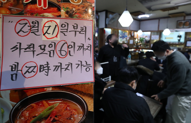 (서울=뉴스1) 김진환 기자 = 지난달 18일 서울 광화문의 한 음식점에 새 거리두기 조정안 문구가 적힌 안내문이 부착되어 있다./사진=뉴스1 