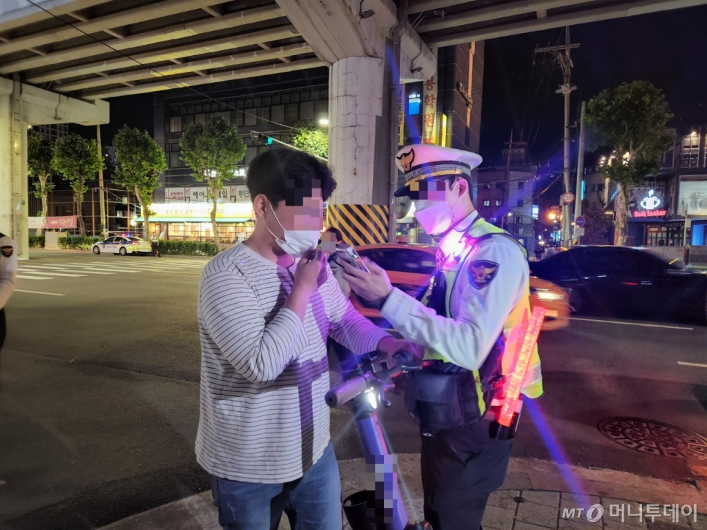 30일 밤 11시25분쯤 서울 광진구 아차산로 일대에서 헬멧을 착용하지 않은 채 음주 상태로 전동킥보드를 타던 시민이 단속에 걸려 음주측정기를 불고 있다. /사진=박수현 기자