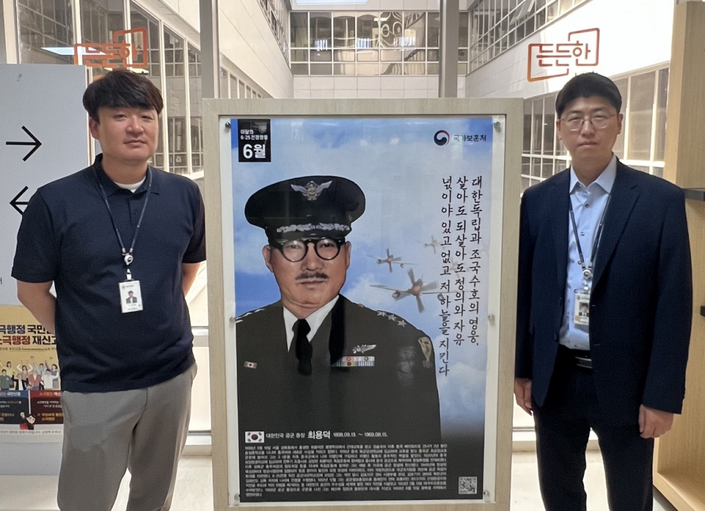 2022년 6월 6·25전쟁영웅으로 뽑힌 최용덕 공군 중장 포스터를 사이에 두고 허근창 주무관(왼쪽)과 성태헌 국가보훈처 사무관이 포즈를 취하고 있다./사진제공=성태헌 국가보훈처 사무관