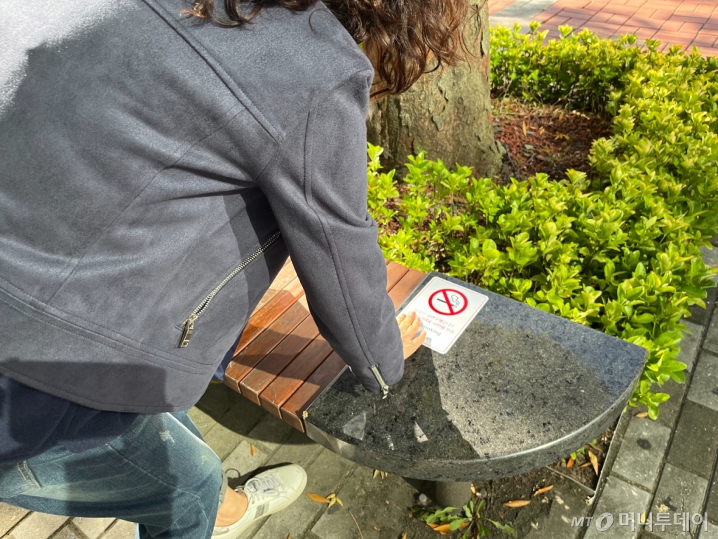 유 주무관이 17일 오후 3시경 서울 마포구 보건소 앞 벤치에 금연 안내 스티커를 부착하고 있다. 단속원들은 흡연 단속뿐 아니라 이렇게 안내 문구 정비 등의 활동도 함께 하고 있다./사진=유예림 기자