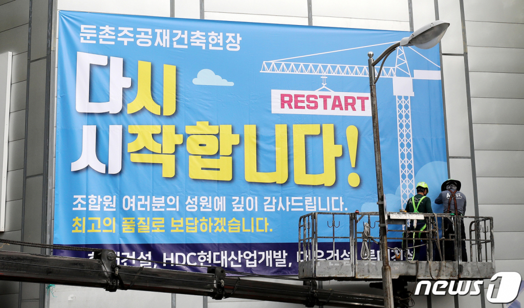 16일 서울 강동구 둔촌주공 재건축 현장에서 관계자들이 공사 재개를 알리는 현수막을 붙이고 있다.  6개월간 멈춰섰던 둔촌주공아파트 재건축 사업이 오는 17일부터 다시 시작된다. 2022.10.16/뉴스1  Copyright ? 뉴스1. All rights reserved. 무단 전재 및 재배포 금지.