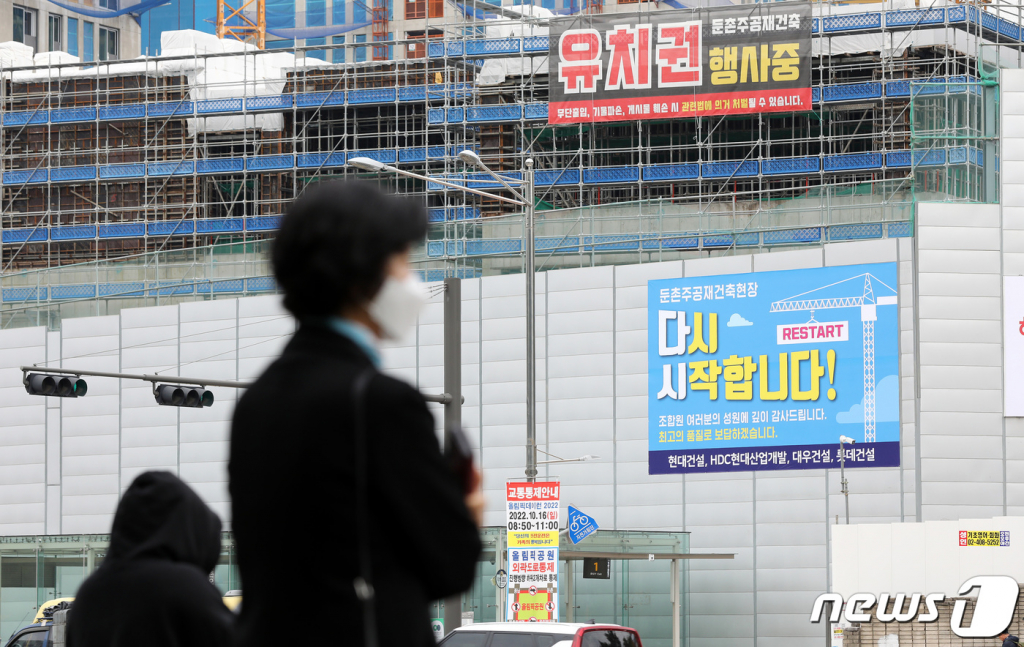 (서울=뉴스1) 박지혜 기자 = 16일 서울 강동구 둔촌주공 재건축 현장에 공사 재개를 알리는 현수막이 붙어 있다.  6개월간 멈춰섰던 둔촌주공아파트 재건축 사업이 오는 17일부터 다시 시작된다. 2022.10.16/뉴스1  Copyright ? 뉴스1. All rights reserved. 무단 전재 및 재배포 금지.