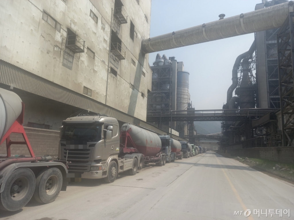 지난 7일 한일시멘트 공장을 가로지르는 국도 매포길 300~400m 구간에 시멘트를 실어나르는 BCT(벌크 시멘트 트레일러)들이 수십대 주차돼있다. 이틀 연속 비가 내렸는데 보통 비가 오면 공사가 멈춰 시멘트 출하가 줄고 재고가 쌓이지만 지난 5~6일 비는 부슬비라서 공사 현장들이 콘크리트를 타설하고 위에 방수포를 덮는 식으로 공사를 했다. 공장 안 시멘트 창고인 '사일로' 앞에도 BCT들이 수십대 있었다. 원래도 공사 성수기인 봄이면 BCT들이 시멘트를 받기 위해 공장에 줄을 선다. 심할 때면 한일시멘트, 성신양회 공장과 인접한 도담역 앞 공터까지 BCT 줄이 늘어져 인근 주민 항의도 받는다. 올해는 시멘트 수요가 더 커 줄이 더 긴 수준이다./사진=김성진 기자.