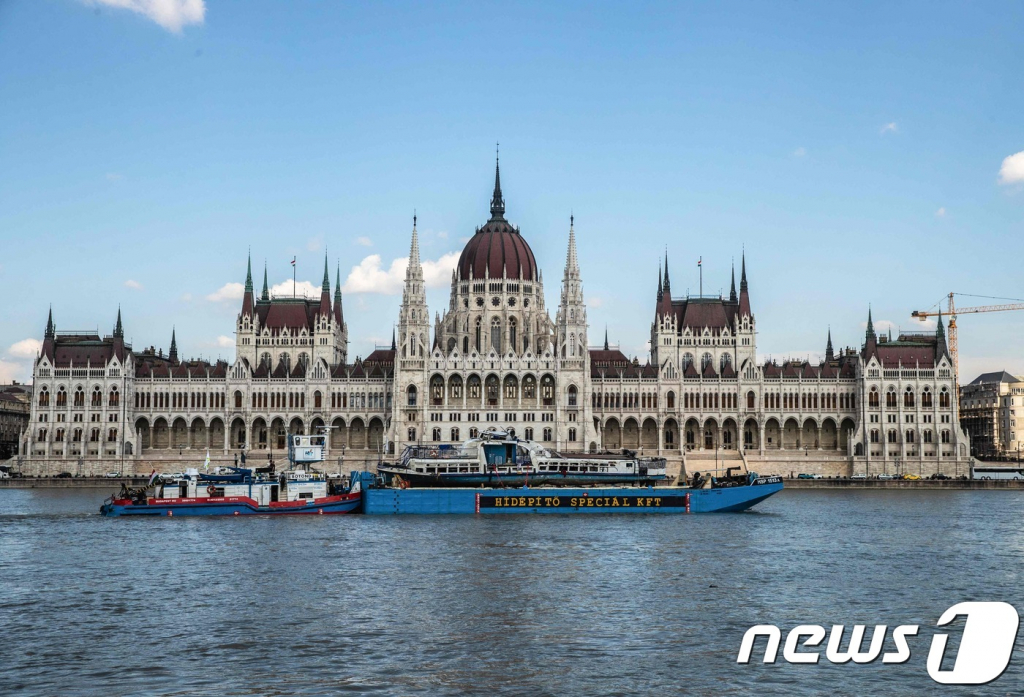 (부다페스트 AFP=뉴스1) 우동명 기자 = 11일(현지시간) 헝가리 부다페스트 다뉴브강 머르기트 다리에서 크레인 클라크 아담호가 침몰 13일만에 허블레아니호를 들어올린 뒤 바지선으로 의사당을 지나 이동하고 있다.   ? AFP=뉴스1  