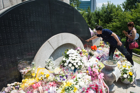 =서울 양재동 양재시민의 숲에 위치한 삼풍백화점 참사 위령탑에서 열린 제20주기 삼풍백화점 참사 추모제에 참석한 유가족들이 헌화 후 희생자의 이름을 찾아보고 있다.2015.6.29/뉴스1  