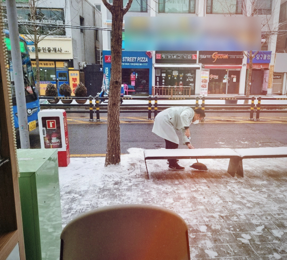 버스정류장에 쌓인 눈을 치우고 있는 신재우(가명) 한스동물병원 원장./사진=한스동물병원