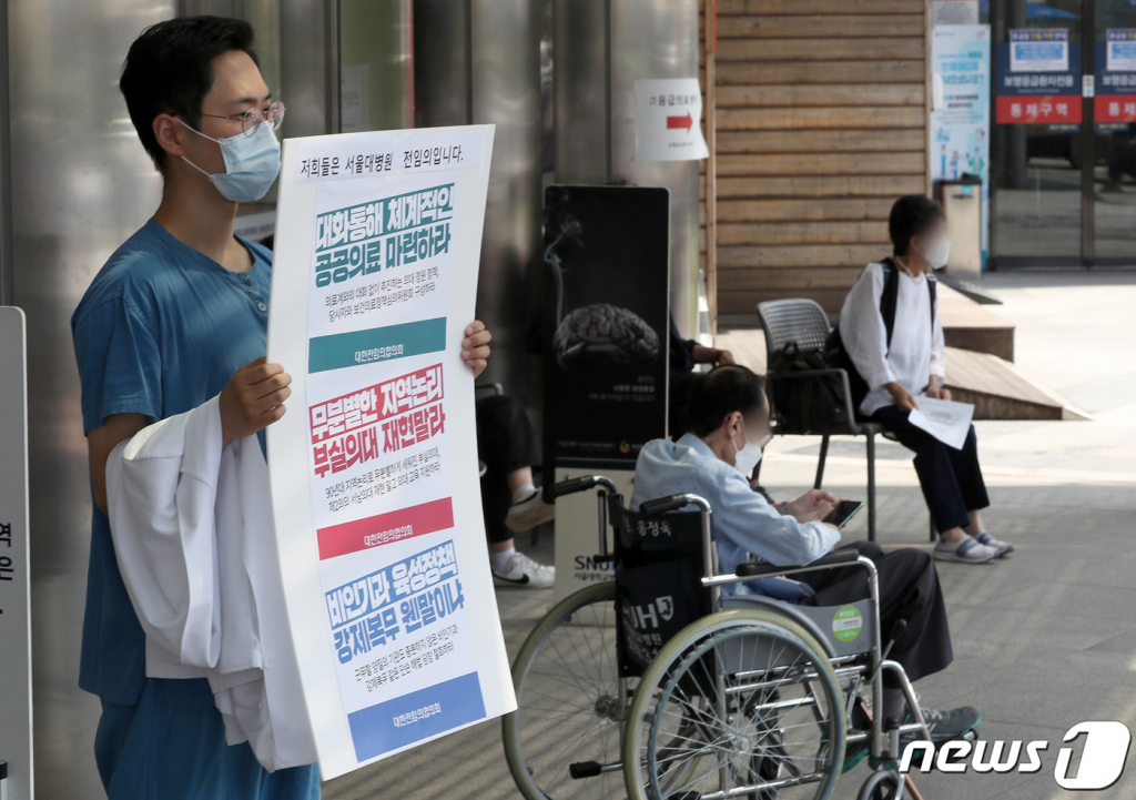 (서울=뉴스1) 이동해 기자 = 대한전임의협의회 소속 전임의들이 25일 서울 종로구 서울대병원 본관 앞에서 의사 가운을 벗어 들고 정부의 의과대학 정원 확대 등 의료정책에 반대하는 손팻말을 들고 있다. 2020.8.25/뉴스1  