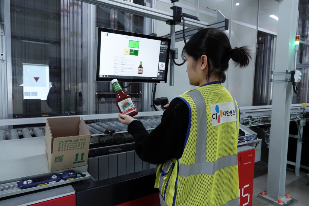 CJ대한통운 인천GDC 오토스토어 출고스테이션에서 작업자가 주문 제품을 출고하고 있다. 주문이 들어오면 피킹 로봇이 실시간으로 제품이 담긴 바구니를 작업자 앞에 전달한다. 작업자는 화면에 뜬 제품 정보와 최적 박스를 확인 후 박스에 제품을 넣으면 된다. 제품이 사람을 찾아가는 'GTP(Goods-To-Person)' 방식. /사진제공=CJ대한통운