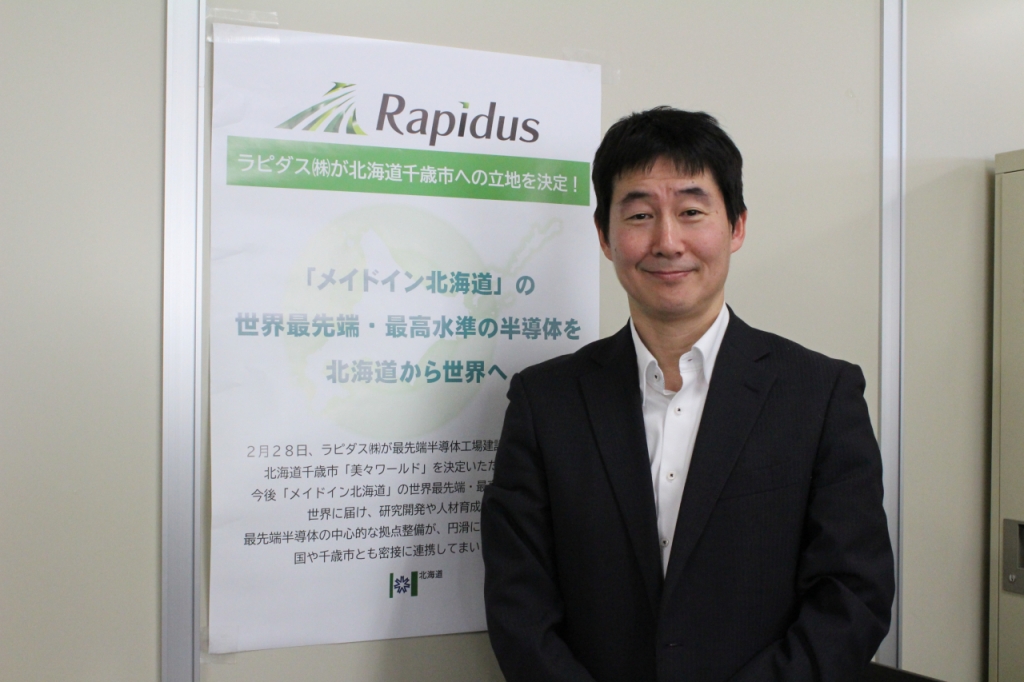 타무라 코지 홋카이도청 반도체전략실 과장이 라피더스의 공장 부지 결정에 대한 안내문 앞에서 기념촬영을 하고 있다./사진=이재윤 기자