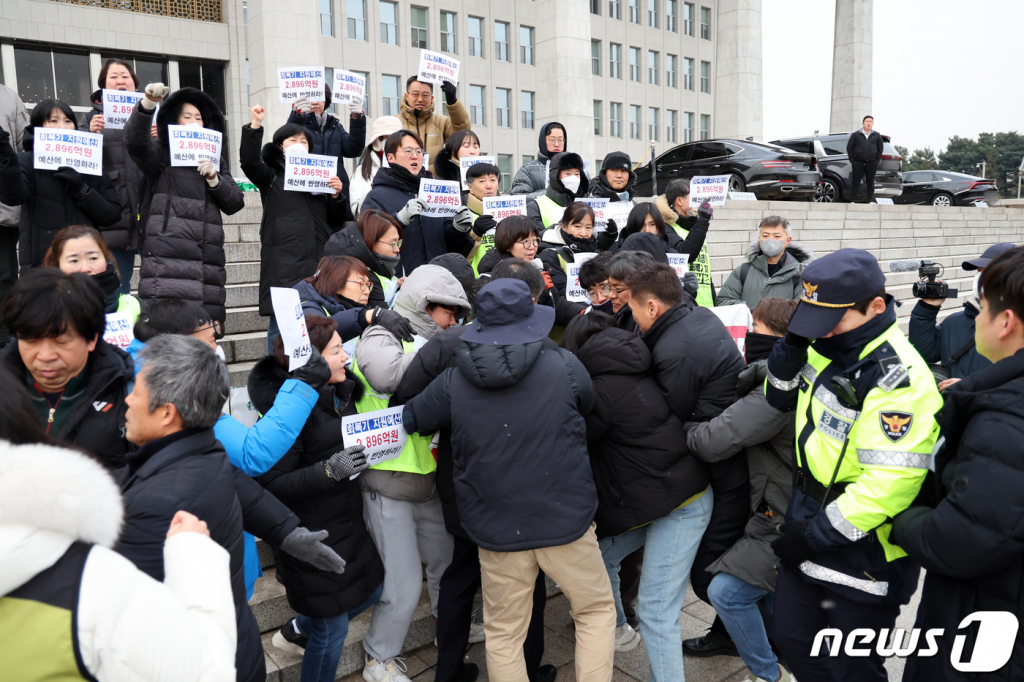 (서울=뉴스1) 황기선 기자 = 민주노총 보건의료노조 조합원이 19일 오후 서울 여의도 국회 본청 계단 앞에서 가진 ‘감염병 대응 공공병원에 대한 회복기 지원 예산 마련 촉구 기자회견’에서 국회 관계자들과 충돌하고 있다.  이날 미신고로 기자회견을 진행한 보건의료노조는 공공병원 예산 반영 촉구를 위해 여·야 예산결산위원회 협상단과의 면담을 요청했다. 2023.12.19/뉴스1  Copyright © 뉴스1. All rights reserved. 무단 전재 및 재배포,  AI학습 이용 금지.