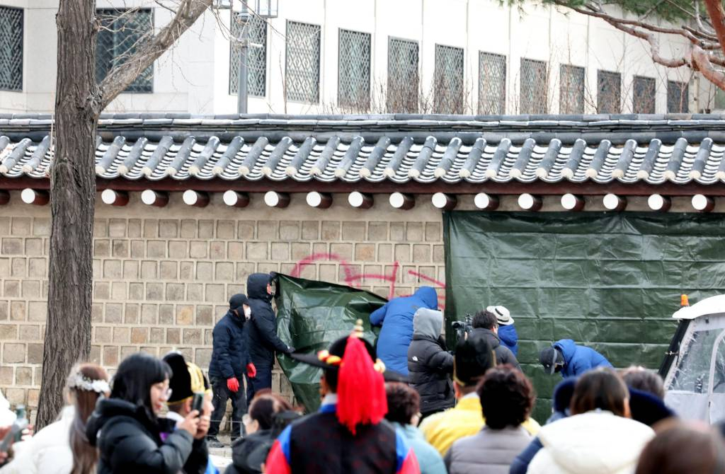 문화재청 궁능유적본부 직원들이 지난 16일 서울 종로구 국립고궁박물관 방향 경복궁 서편에서 스프레이 낙서로 훼손된 담벼락을 천으로 덮고 있다./사진=뉴시스