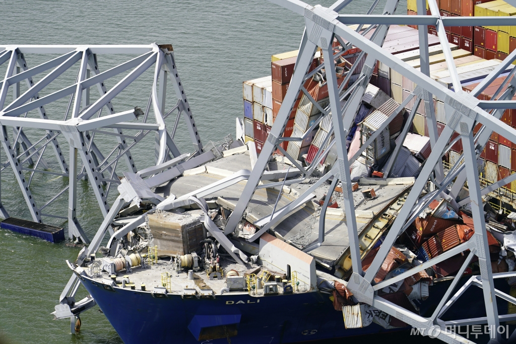 [볼티모어=AP/뉴시스] 27일(현지시각) 미 메릴랜드주 볼티모어항 입구의 프랜시스 스콧 키 브리지를 무너트린 대형 화물선 '달리'가 다리 구조물에 걸려 있다. 피트 부티지지 미 교통부 장관은 “다리를 복구하고 항구를 재개방하기까지 얼마나 오랜 시간이 걸릴지 확실하게 판단하기에는 이르다”라고 밝혀 볼티모어 항구 가동 중단의 장기화가 우려되고 있다. 2024.03.28. /사진=민경찬