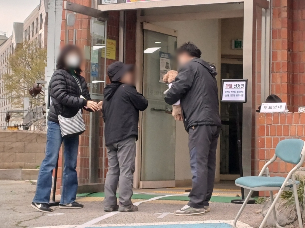 5일 오전 8시30분쯤 반려견을 동반한 유권자가 투표소 내부에 반려견 출입이 불가하다고 안내받자 선거사무원에게 반려견을 맡기고 투표하러 들어가고 있다/사진=오석진 기자