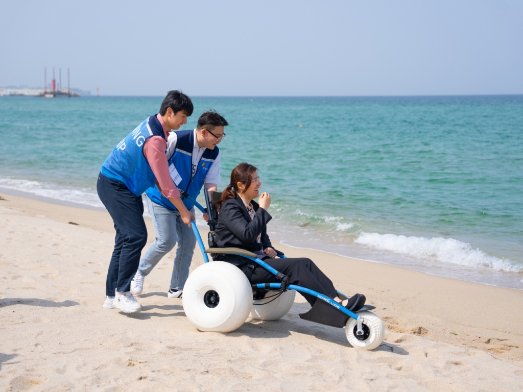 장미란 문체부 차관이 19일 강릉 연곡해변에서 '행복 나눔여행' 참가자들과 함께 수상 휠체어를 직접 체험해보고 있다.