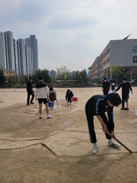 큰 나무 막대기로 운동장에 밑그림을 그리고 있는 1학년 8반 학생들./사진=김동은 선생님 제공