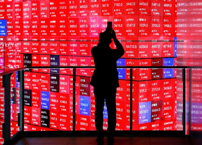 지난 2월 일본 도쿄 증권거래소 주식 시황 전광판이 온통 빨간색으로 칠해진 모습을 방문객이 휴대전화로 찍고 있다./로이터=뉴스1