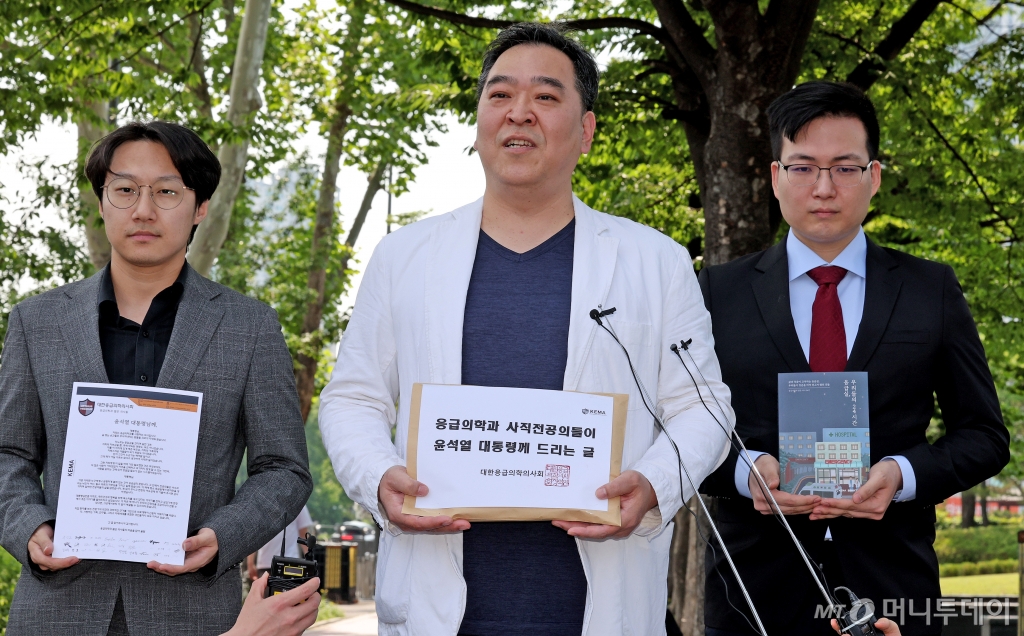 (서울=뉴스1) 장수영 기자 = 이형민 대한응급의학의사회 회장(가운데)과 사직전공의들이 22일 오후 서울 용산구 대통령실 앞에서 윤 대통령에게 전달할 '응급의학과 사직전공의들이 윤석열 대통령께 드리는 글'과 '응급실, 우리들의 24시간'책을 들어보이고 있다. 2024.5.22/뉴스1  Copyright © 뉴스1. All rights reserved. 무단 전재 및 재배포,  AI학습 이용 금지. /사진=(서울=뉴스1) 장수영 기자