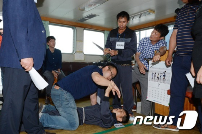 인도양에서 조업 중이던 광현 803호에서 한국인 선장과 기관장을 살해한 베트남 선원들이 2016년 7월 5일 부산해경 부두에 정박한 100여톤급 방제정에서 몸싸움 중 선장의 목을 잡고 살해하던 순간을 재연하고 있다. /사진=뉴스1