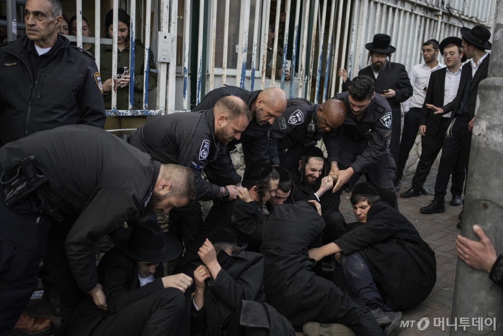 지난 2월 4일(현지시각) 이스라엘 예루살렘의 한 징병소 앞에서 이스라엘 경찰관들이 군 징집에 반대하며 시위 중인 초정통파 유대교도 남성들과 몸싸움을 벌이고 있다. 이스라엘에서 초정통파 유대교 신자인 '하레디'의 병역 면제를 없애고 이들에 대한 징집 필요성이 대두되면서 '하레디'의 반발도 커지고 있다/AP=뉴시스