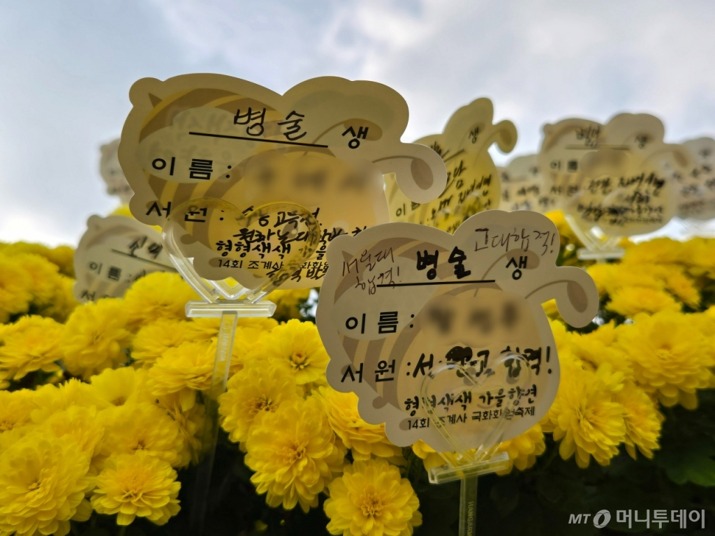 노란 국화꽃 사이에는 수험생 가족들이 작성한 '서원 종이'가 빼곡히 꽂혀있었다./사진=이혜수 기자   