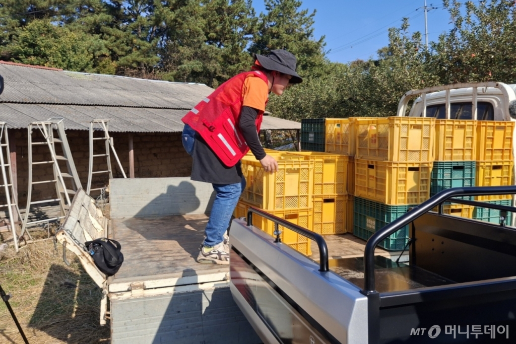 이은주씨가 RT100에서 사과상자를 내리고 있다. 트럭에 맞춰 적재함의 높이를 조절할 수 있다./사진=김성진 기자.