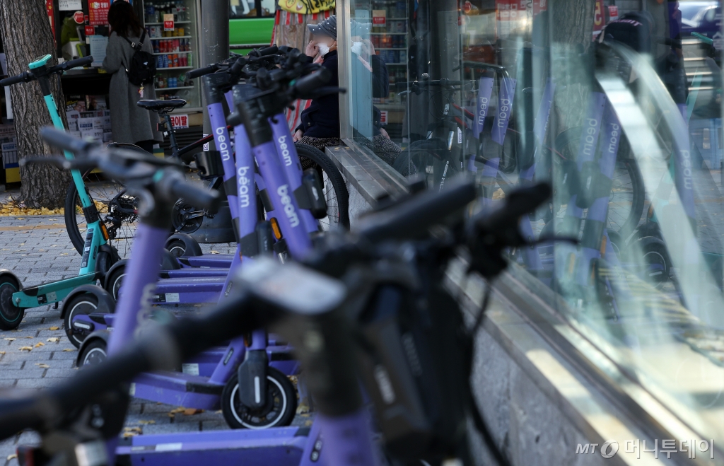 (서울=뉴스1) 이동해 기자 = 19일 서울 시내에 전동킥보드가 세워져 있다.  19일 업계에 따르면 경찰청은 늦어도 내년 1월까지 유관기관 단체와 협의해 전동킥보드 등 개인형 이동장치(PM) 전용 운전면허 신설과 관련한 합리적 안을 도출할 계획이라고 전했다. 현재 도로교통법상 공유 전동킥보드는 제2종 원동기장치자전거 면허 또는 그 이상(제2종 소형·보통면허, 제1종 보통면허 등)의 운전면허 소지자만 이용할 수 있다. 면허 취득 방식으로는 세 가지가 거론된다. 학과시험(필기시험)만 치르거나, 학과와 기능시험(실습시험)을 함께 치르거나, 온라인 교육만 이수하는 방안 등이 있다. 2024.11.19/뉴스1  Copyright © 뉴스1. All rights reserved. 무단 전재 및 재배포,  AI학습 이용 금지. /사진=(서울=뉴스1) 이동해 기자