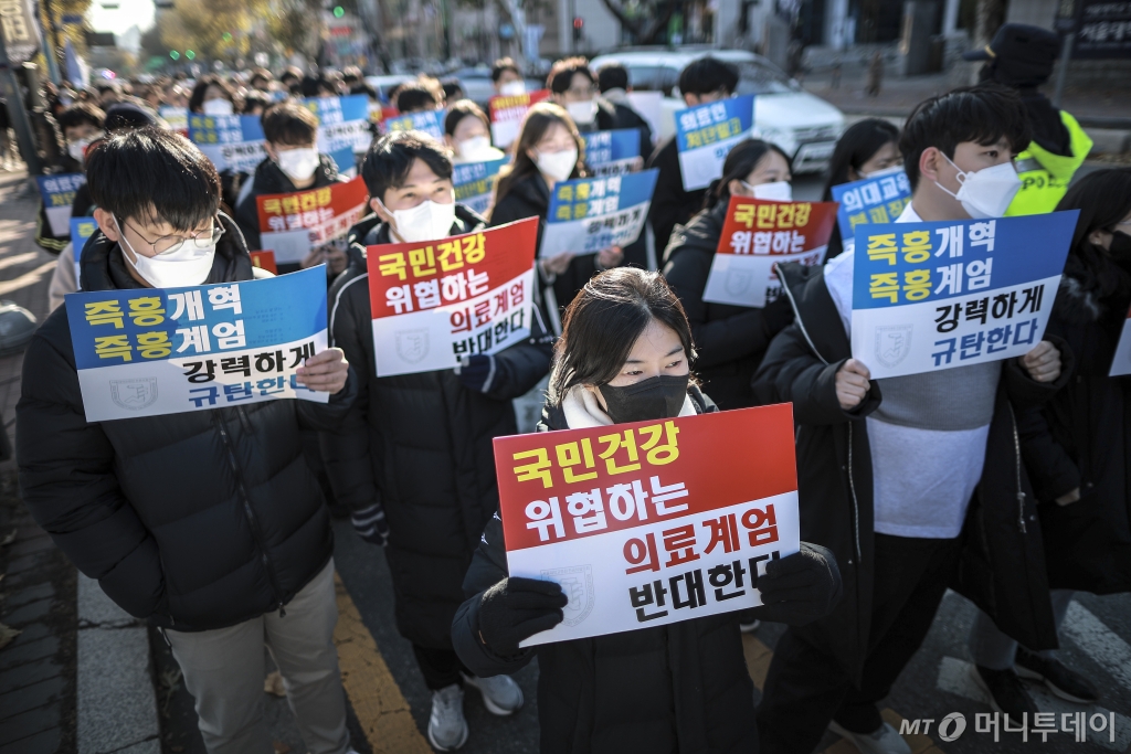 [서울=뉴시스] 정병혁 기자 = 8일 서울 종로구 대학로에서 열린 서울대병원 전공의협의회 비상대책위원회 ‘젊은 의사 의료계엄 규탄 집회’에서 사직 전공의를 비롯한 젊은 의사들이 피켓을 들고 있다. 2024.12.08. jhope@newsis.com /사진=정병혁