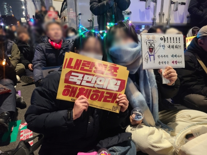 9일 오후 7시 30세 조모씨와 오모씨가 시위 현장에서 '내려와라'라는 곡을 따라 불렀다. 어제 집회에서 처음 들은 노래지만 열성적으로 따라 부르던 이들은 이내 입김이 나오는 추운 날씨에도 덥다며 손부채를 부쳤다./사진=이찬종 기자