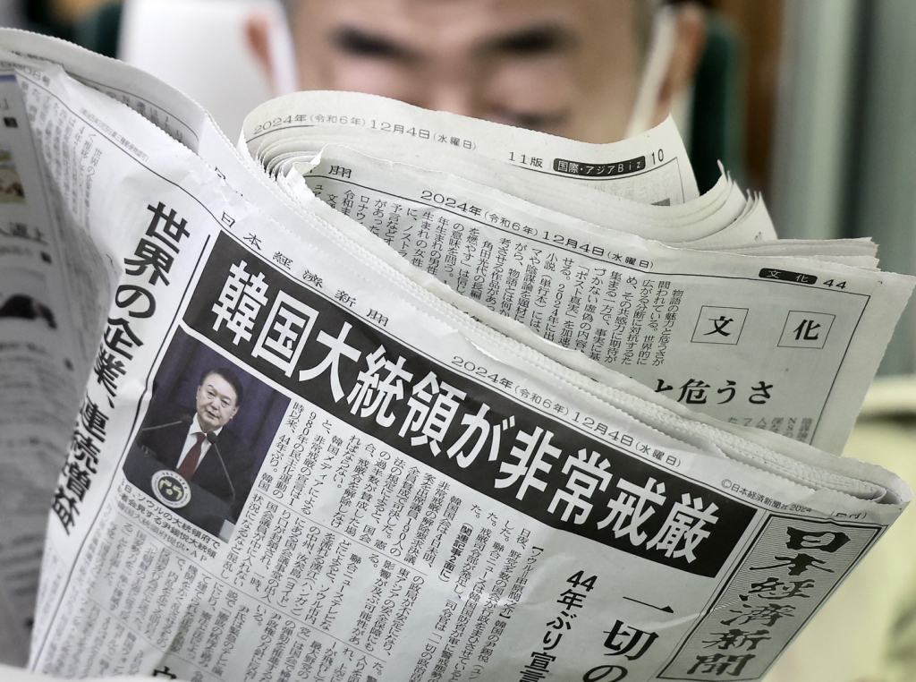  윤석열 대통령의 비상계엄 관련 소식이 4일 일본 니혼게이자이신문 조간 1면에 보도되어 일본 오사카우메다역에서 한 시민이 신문을 읽고 있다. 2024.12.04./사진=뉴시스