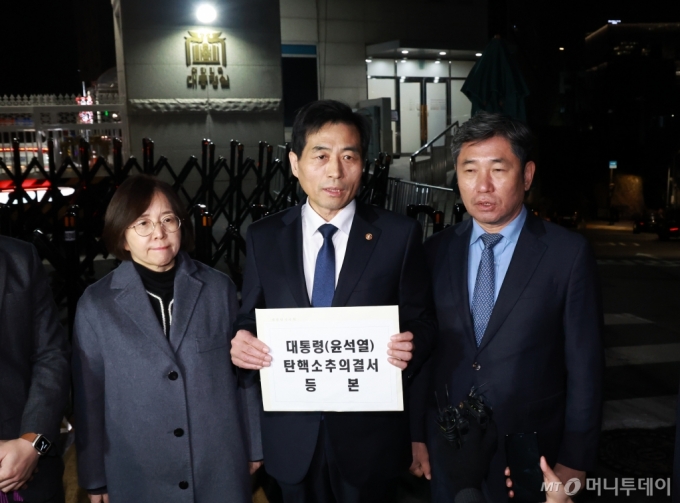 [서울=뉴시스] 조수정 기자 = 윤석열 대통령의 국회 탄핵소추안이 가결된 14일 김민기(가운데) 국회 사무총장이 탄핵소추의결서를 송달하기 위해 서울 용산 대통령실 청사 입구로 들어서며 발언하고 있다. 오른쪽은 조오섭 국회의장 비서실장. 탄핵소추의결서가 대통령실에 송달되는 즉시 윤 대통령의 직무가 정지된다. (대통령실통신사진기자단) 2024.12.14. chocrystal@newsis.com /사진=조수정