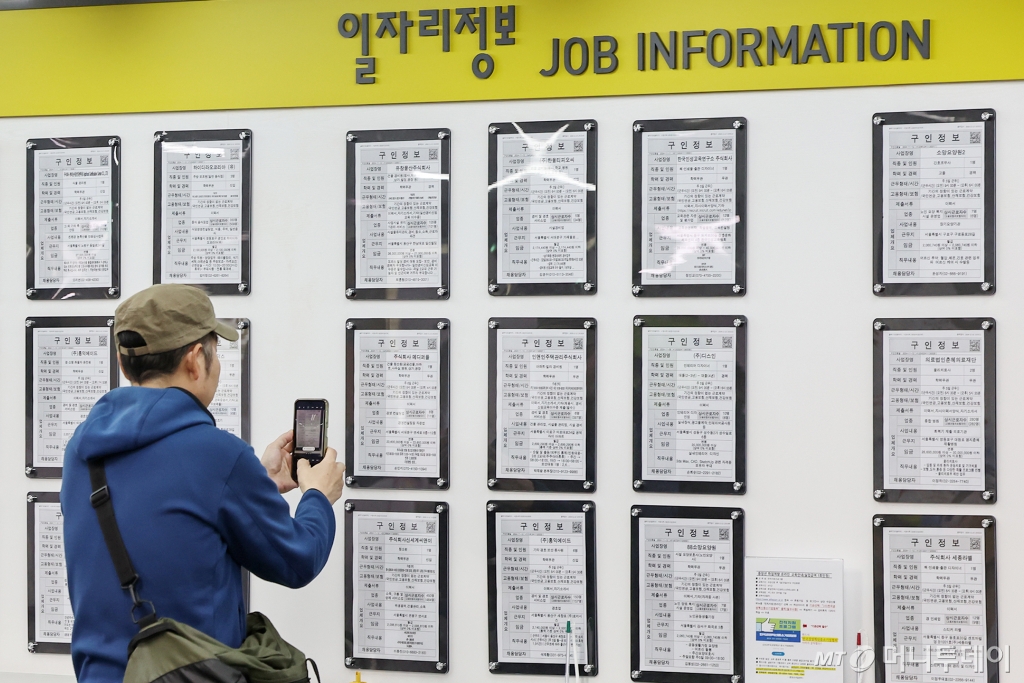 한 구직자가 일자리 정보 게시판 속 구인업체 정보를 휴대전화 카메라에 담고 있다. /사진=뉴스1