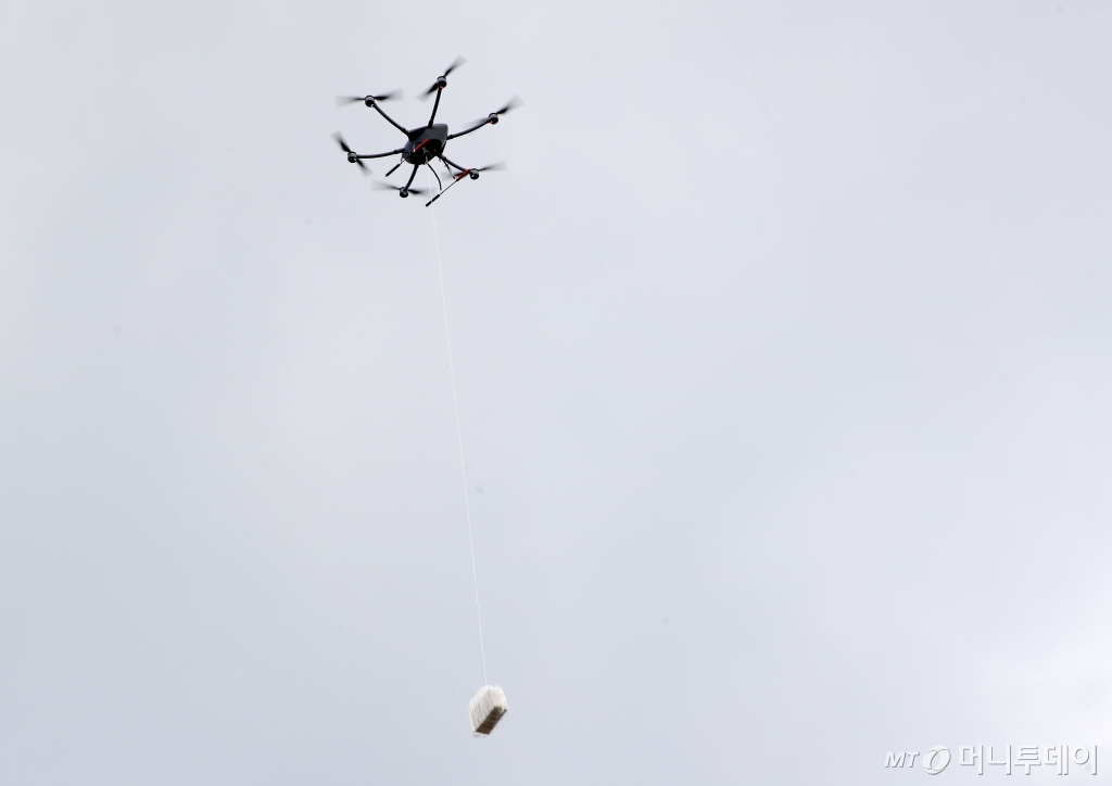 (부산=뉴스1) 윤일지 기자 = 26일 오후 부산 영도구 국립한국해양대학교 배송거점센터에서 전국 최초로 'K-드론 배송 표준안'을 적용한 항만 드론 배송 서비스 시연회가 진행되고 있다.   항만 드론 배송 서비스는 매일 오전 11시부터 오후 7시까지 나라온(NARAON) 애플리케이션을 통해 물품을 주문하면 이용 가능하다. 배송 지역은 부산항 묘박지(11곳), 유어장 낚시터(4곳), 조도방파제(2곳)로 묘박지는 10만 원, 나머지는 3000원을 기본 배송비로 책정했다. 2024.11.26/뉴스1  Copyright © 뉴스1. All rights reserved. 무단 전재 및 재배포,  AI학습 이용 금지. /사진=(부산=뉴스1) 윤일지 기자
