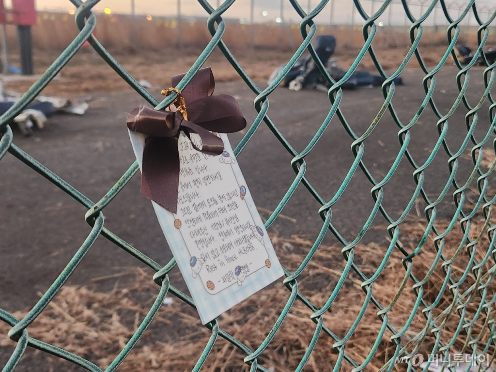 1일 전남 무안국제공항 '무안 참사' 사고 현장 인근에 걸린 파일럿 지망생의 메모. 메모에는 "이번 사고로 유명을 달리한 희생자들의 명복을 빈다"며 "끝까지 요크를 놓지 않으시고 안전하게 착륙하기 위해 최선을 다해주신 기장·부기장님 존경한다. 천국에서 평안하시길 잊지 않고 추모하며 기억하겠다"는 내용이 담겼다. 철장 뒤로 사고 기체 잔해가 보인다./사진=최지은 기자