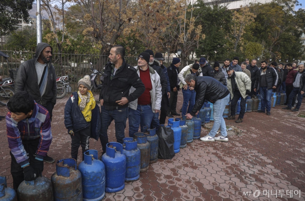 [다마스쿠스=AP/뉴시스] 지난해 12월 31일(현지시각) 시리아 다마스쿠스 거리에서 가스를 사려는 사람들이 가스통을 놓고 길게 줄 서 있다. 2025.01.02. /사진=민경찬