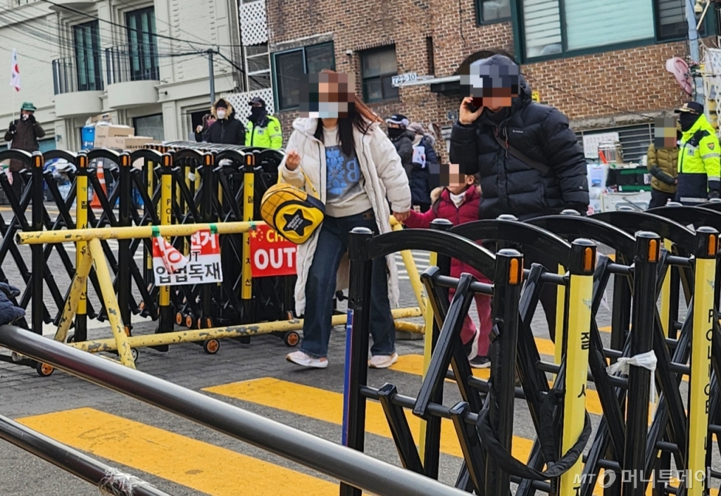 13일 오전 서울 한남동 대통령 관저 근처 한남초등학교 학생이 엄마 손을 잡고 등교하고 있다. 한남초는 대통령 관저 진입로에서 불과 50여 m 떨어져 있다. 윤석열 대통령을 지지하는 보수단체 회원들의 진입을 막고자 학교 정문에 폴리스라인(경찰저지선)이 설치됐다./사진=송정현 기자 