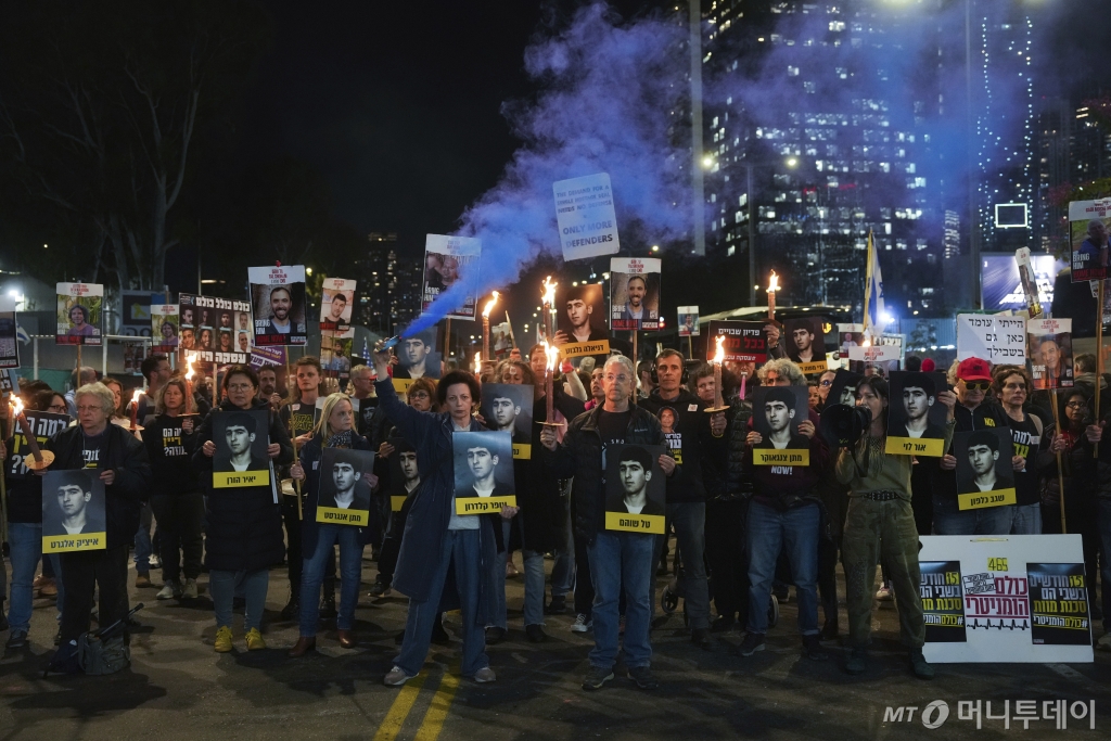 [텔아비브=AP/뉴시스] 13일(현지 시간) 이스라엘 텔아비브에서 하마스에 억류된 인질들의 즉각적인 석방을 촉구하는 시위대가 인질 사진과 횃불을 들고 있다. 2025.01.14. /사진=민경찬