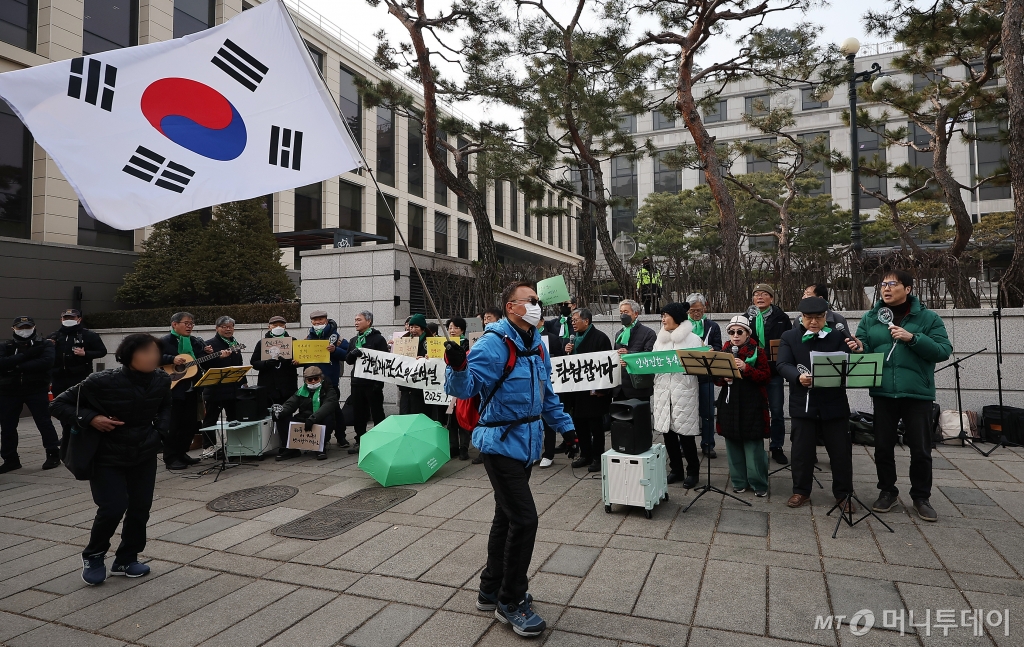 내란 우두머리 혐의로 구속된 윤석열 대통령의 탄핵 사건 3차 변론을 하루 앞둔 20일 오후 서울 종로구 헌법재판소 앞에서 한 윤 대통령 지지자가 태극기를 흔들며 전원일치 파면 촉구 기자회견 앞을 지나가고 있다. /사진=뉴스1