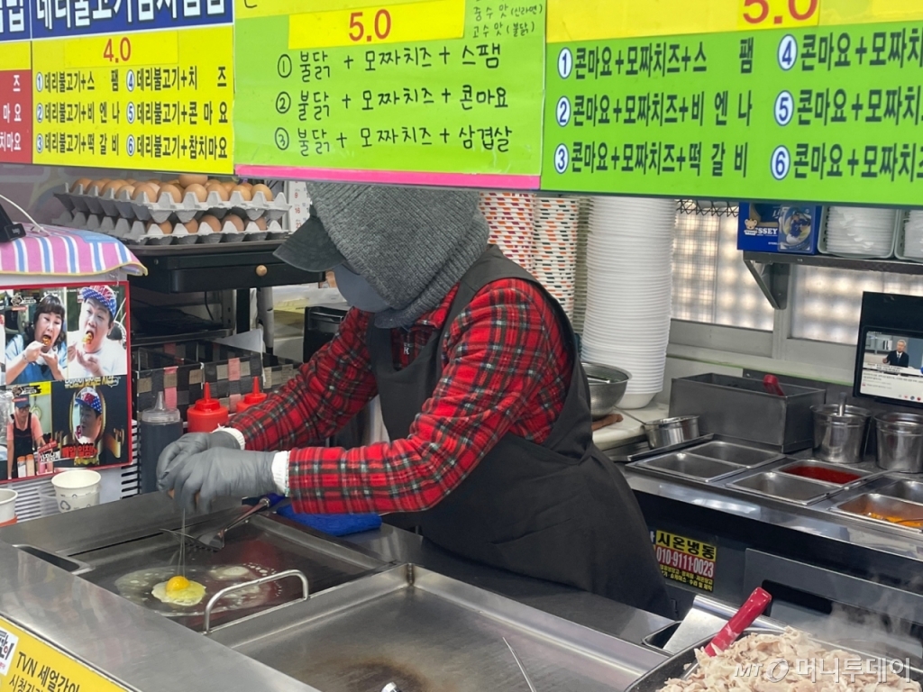 7일 낮 12시쯤 서울 동작구 노량진 컵밥 거리에서 한 상인이 털모자와 마스크를 착용하고 요리를 하고 있다. /사진=이현수 기자.